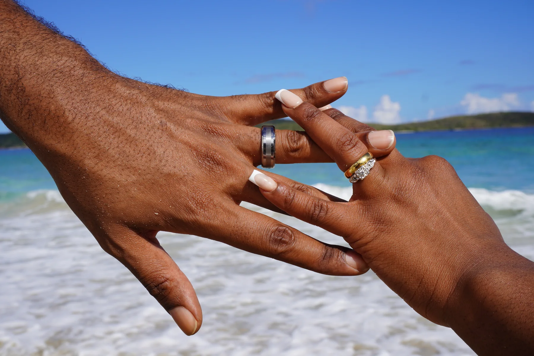 Wedding rings held up against the ocean